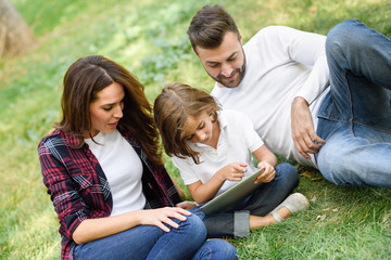 Happy family in a urban park playing with tablet computer