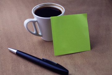Cup of coffee with blank sheet of paper and pen.