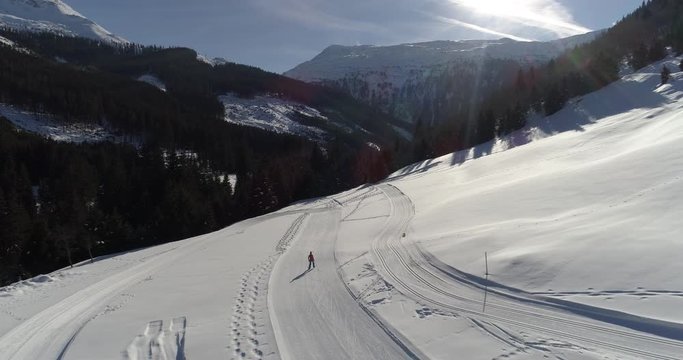 Woman cross-country skiing in a idyllic winter nature in the Alps. Aerial view from the drone