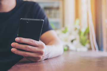 A man holing and using on smart phone in modern cafe