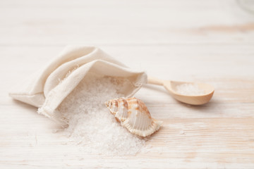 Fototapeta na wymiar sea salt in the bag and shells on a white wooden background