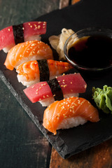 Sashimi and sushi rolls on a stone slatter. Sushi set with salmon, prawns, soy souce, wasabi and ginger. Traditional Japanese cuisine.