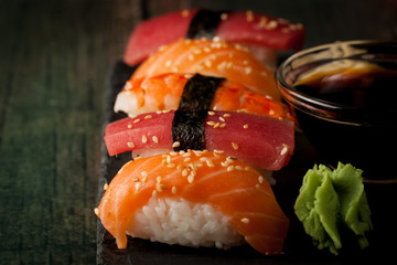 Sashimi and sushi rolls on a stone slatter. Sushi set with salmon, prawns, soy souce, wasabi and ginger. Traditional Japanese cuisine.