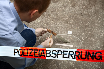 Police tape in Germany at the crime scene with the inscription in German "police cordon." Crime Scene Investigation. The investigator works. Search for evidence of a crime. Knife. Murder.