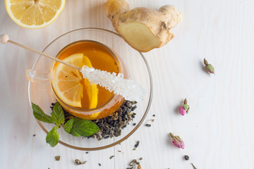 A glass cup of green natural tea with ginger, lemon, mint and honey on wooden rustic background. Healthy drink.
