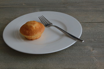 Kleiner Kuchen auf weissem Teller mit Gabel