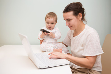 mom and baby. a young mother working with laptop in kitchen