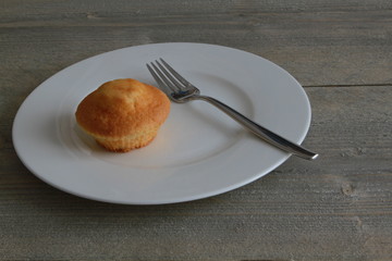 Kleiner Kuchen auf weissem Teller mit Gabel