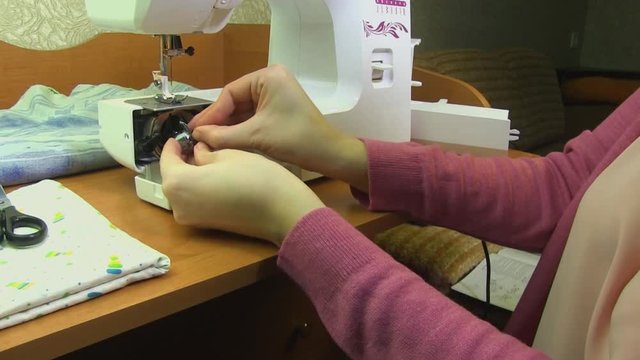 A Woman Is Learning To Insert A Bobin Case Into A Sewing Machine