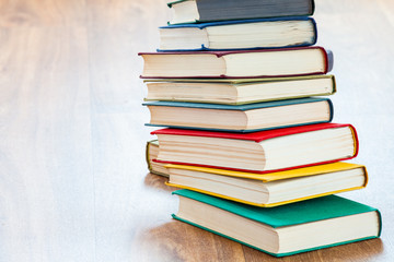 the lying multi-colored books on a wooden table.