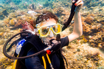 Woman in vacation scuba diving to tropical coral reef