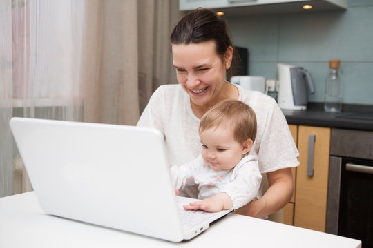 mom and baby. a young mother working with laptop in kitchen