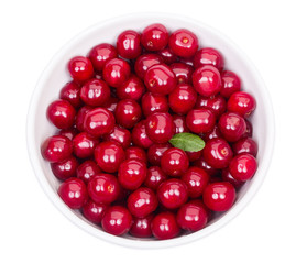 Bowl of fresh red cherries and green leaf isolated on a white ba