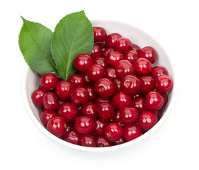 Bowl of fresh red cherries and green leaves isolated on a white