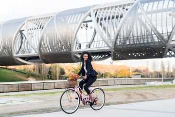 Fototapeta premium Business black woman riding a vintage bicycle in the city