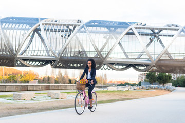Business black woman riding a vintage bicycle in the city