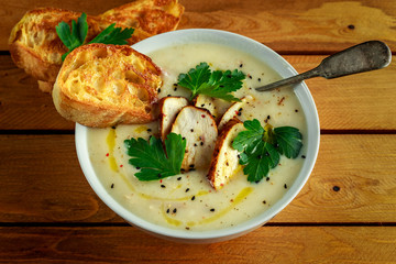 Creamy chicken soup with vegetables in bowl with chiabatta toast, parsley and nigela seeds sprinkle