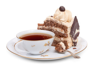 A piece of chocolate cake on a round plate with a cup of tea and