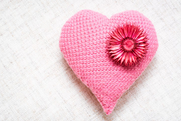 Fototapeta na wymiar Knitted heart with dried flowers on a linen napkin