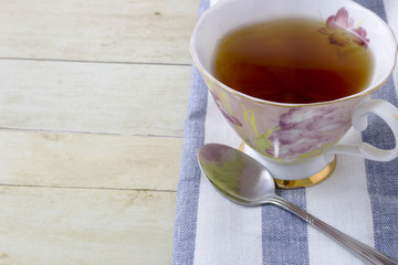 Cup of tea with napkin on light wood background
