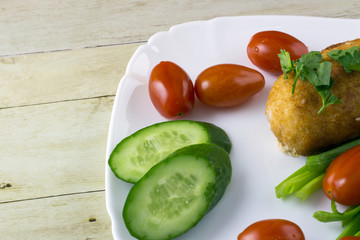 Chicken cordon bleu with vegetables on light wood background