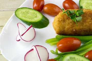 Chicken cordon bleu with vegetables on light wood background