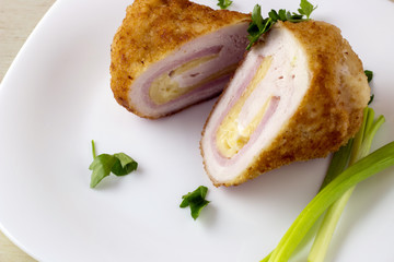 Chicken cordon bleu with vegetables on light wood background