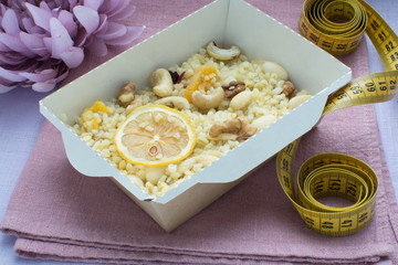 Каша из булгура с орехами в крафт коробке, на заднем фоне пион и сантиметровая лента 