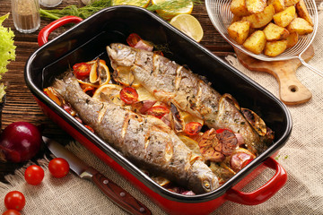 Baked trout with vegetables and potatoes in pan