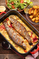 Baked trout with lemon sauce and vegetables in a pan