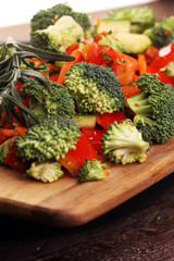 Fresh vegetables on the cutting board are falling in the wok. Co