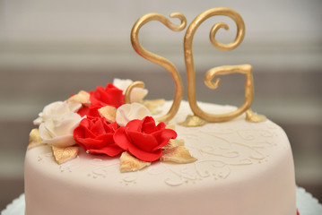 Sweet cakes in the form of red roses decorate the wedding cake with more decorative twigs of white cream. Photographed at a wedding in Novi Sad, Serbia.