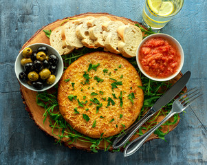 Spanish classic tortilla with potatoes, olives, tomatoes, rucola, bread and herbs.