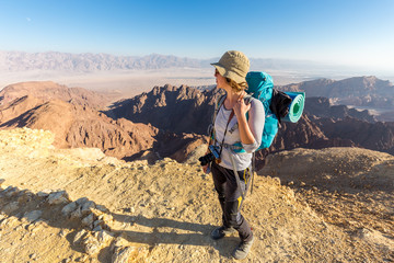 Backpacker young woman standing desert mountain edge canyon view - obrazy, fototapety, plakaty