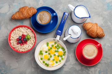 Traditional breakfast with eggs, oatmeal porridge, croissants and coffee. Top view