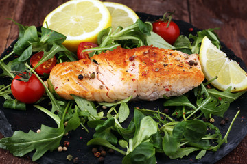 baked salmon grilled pepper lemon on a plate with lettuce leaves