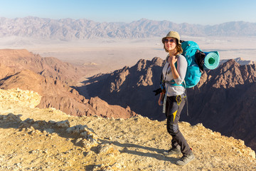 Backpacker young woman standing desert mountain edge canyon view