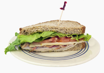 Half a club sandwich on whole grain wheat bread. served on a plate. Isolated.