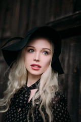 Beautiful attractive and stylish girl wearing black hat standing posing in city. Nude makeup, best daily hairstyle and great fashion glamour country style. Retouched photo