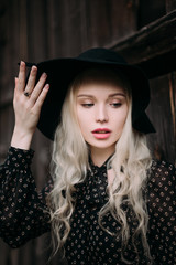 Beautiful attractive and stylish girl wearing black hat standing posing in city. Nude makeup, best daily hairstyle and great fashion glamour country style. Retouched photo