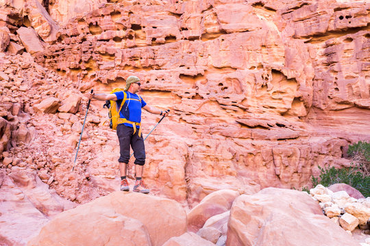 Backpacker tourist man standing desert stone canyon mountain trail.