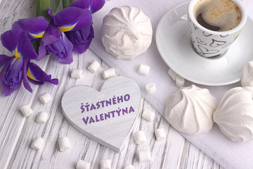 Still life with cup of coffe marshmallow zephyr iris flowers heart sign with lettering Happy Valentines Day in Czech on white wooden background.