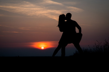 Fototapeta na wymiar silhouette teenager lovers couple with sun between on sunset dusk sky background: black shadow hand drawn of people hug and kiss people:passion in love concept:decoration,design,valentines