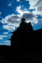 Silhouette of a wooden church against the blue sky.