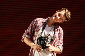 stylish hipster man holding old retro analog photo camera and sm