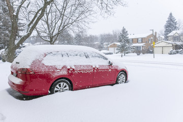 Snow Falling on a Red Car in the Suburb