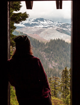 Person looking at view of snow capped mountains through doorway, Elfin Lakes, Canada, British Columbia, North America 