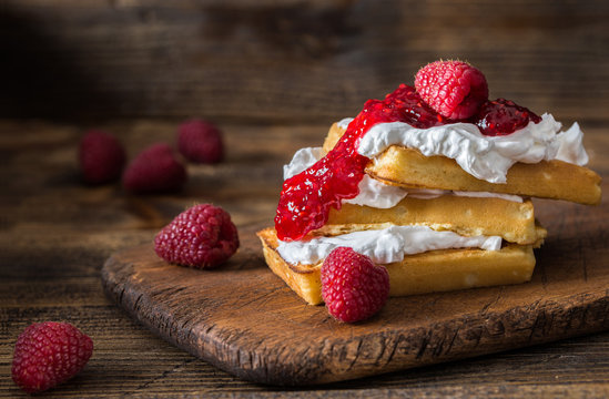 Belgian waffles with raspberries and double cream on rustic tabl