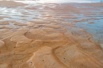 Nang Thong Beach at low tide in Khao Lak, Thailand. Seaside with sand dunes and reflection of blue sky in water. Natural background.