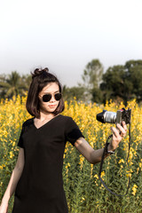 Beautiful Asian girl taking pictures on the flowers field